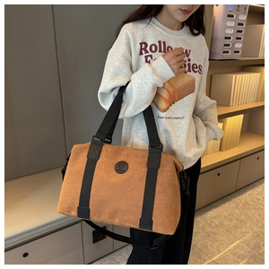 Brown suede travel bag shown on shoulder in a lifestyle setting for casual fashion
