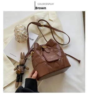 Close-up of brown quilted bucket bag with a cute rabbit charm on a white blazer
