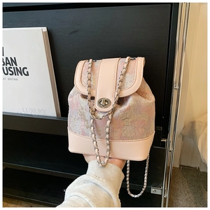 Detail of pink jacquard bucket backpack with silver turn-lock and chain strap