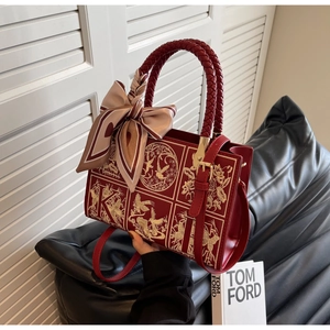 Detail of red leather bag featuring bird floral embroidery and woven handle with silk scarf