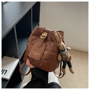 Close-up of brown quilted bucket bag with a cute rabbit charm and gold buckle