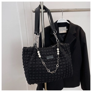 Detail of black bubble texture tote bag featuring pearl flower chain and leather strap