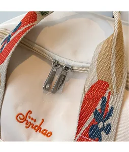 Détail du sac en sergé beige clair avec poignées tissées colorées et zips métalliques