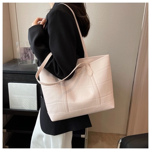 Detailed side view of beige large tote bag with embossed crocodile leather texture
