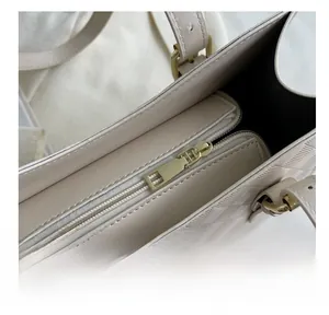 Detail of smooth gold zipper and embossed checkerboard texture on cream tote bag