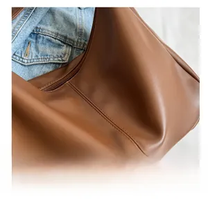 Detailed close-up of vertical stitching on dark brown leather tote bag with zipper