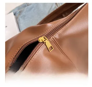 Detailed close-up of the smooth gold-tone zipper and stitching on the brown leather bag
