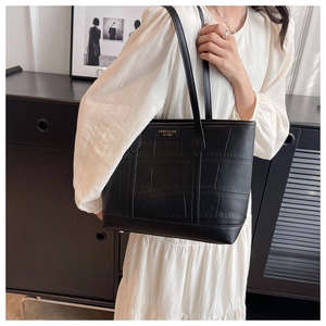 Close-up of black crocodile pattern leather tote bag with elegant gold letter branding
