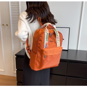 Détail du sac à dos en tissu orange avec bretelles élégantes aux motifs ethniques