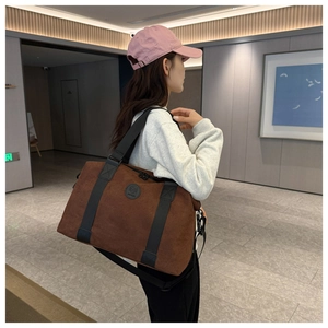 Detail view of large dark brown travel bag featuring reinforced handles and a shoulder strap