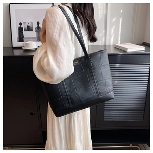 Detail of black embossed tote bag with gold logo and spacious leather texture