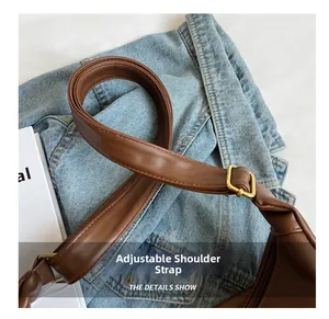 Detail of adjustable brown leather shoulder strap with gold buckle and precise stitching