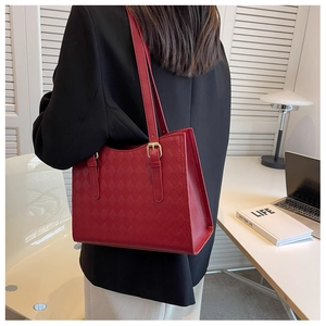 Detail of red quilted faux leather tote bag with adjustable shoulder strap and gold hardware