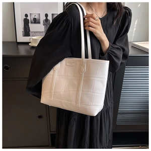 Detailed view of large white croc-effect tote bag on model in a minimalist setting