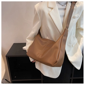 Detailed view of brown faux leather crossbody bag with vertical stitching on model