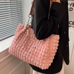 Pink pleated cloud tote bag with pearl chain strap worn by a model in black blazer
