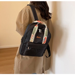 Vue arrière du modèle portant un sac à dos en nylon noir avec poignées jacquard fleuries