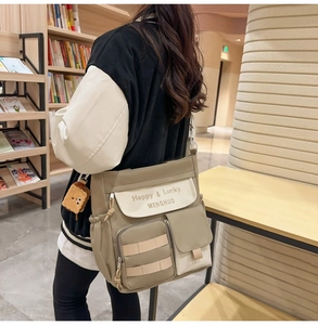 Detail of khaki oxford tote bag with multi-pocket design and cute cookie pendant
