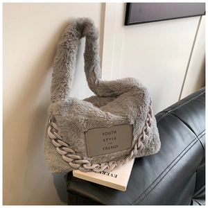 Detail of grey faux fur tote bag with leather logo patch and purple chain accessory