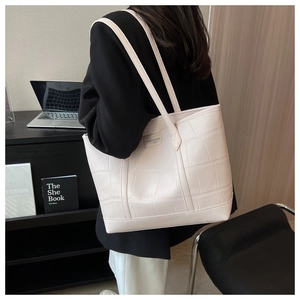 Detail of cream white tote bag featuring premium crocodile embossed leather texture