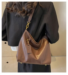 Detail of dark brown hobo bag showing oil-wax texture and golden hardware accents