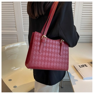 Close-up of red quilted tote bag with golden adjustable buckle and sleek PU leather texture