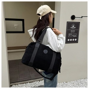 Lifestyle shot of large black canvas travel bag worn as crossbody in a cafe setting