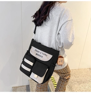 Detail of black and white Oxford tote bag with multi-pockets and cute plush charm