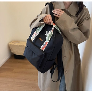 Détail du sac à dos en nylon noir avec poignée brodée colorée et logo sur le devant
