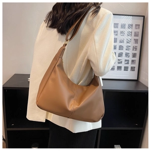 Detailed view of caramel brown hobo bag with vertical stitching and gold ring details