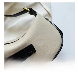 Detailed close-up of beige suede shoulder bag with black leather trim and gold buckle
