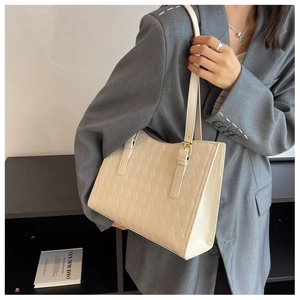 Close-up of quilted cream tote bag with adjustable golden buckle and leather strap