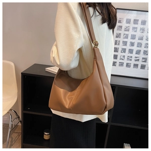 Close-up of caramel brown leather shoulder bag with adjustable strap and metal hardware