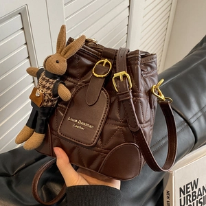 Deep coffee quilted leather bucket bag with gold hardware and a cute bunny charm