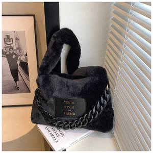Detailed shot of black faux fur tote bag with chunky chain and golden text patch