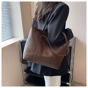 Detailed view of crocodile-patterned tote bag worn on shoulder in professional setting