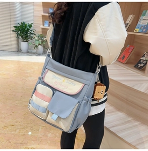 Detail of blue canvas tote bag with triple pockets and a plush toast charm in a library