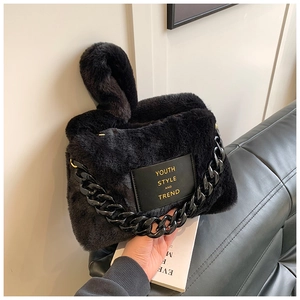 Detail of black faux fur tote bag with gold lettering patch and thick plastic chain strap