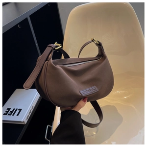 Detail of dark brown crescent bag with soft matte texture and adjustable strap