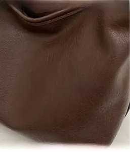 Close-up of premium dark brown PU leather texture with neat stitching on a dumpling bag