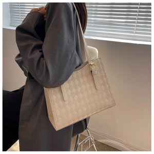 Detail of a beige quilted tote bag with smooth leather finish and gold hardware strap