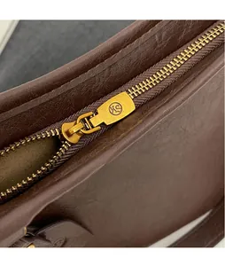 Detail of dark brown leather bag with gold KS metal zipper and smooth finish