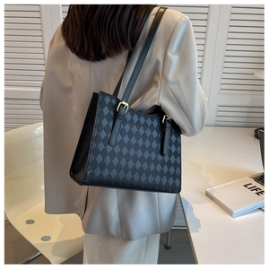 Detail of black quilted tote bag with adjustable strap and golden metal buckle