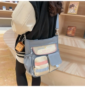 Detail of light blue Oxford tote bag featuring contrast flap and plush toast keychain