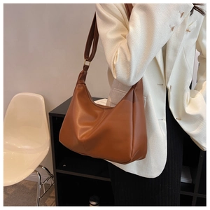Detail of soft brown leather hobo bag with wide shoulder strap and gold hardware accents