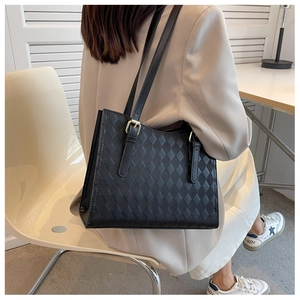 Detail of black quilted tote bag with gold hardware worn on shoulder for commuting