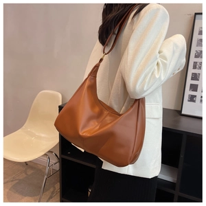 Brown matte leather hobo bag with minimalist central stitching on a female model