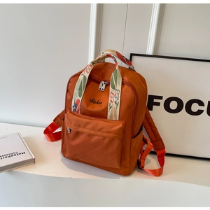 Détail du sac à dos en nylon caramel avec bandoulière brodée et poche avant zippée