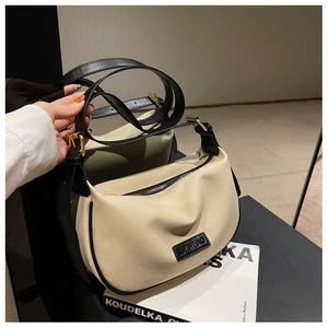 Detail of off-white leather dumpling bag with black piping and gold-tone metal buckle