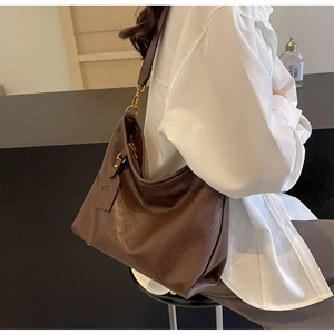 Close-up of vintage brown leather texture and golden metal buckle on large hobo bag